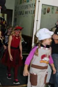 students parading in costume into the gym