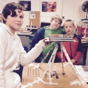 Three students put books on their structure to test its stability