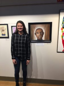 student standing in front of art work