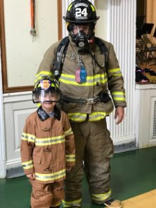 fire fighter with student in fire coat and hat